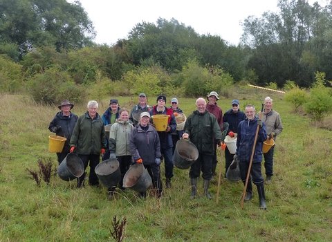 Happy group of volunteers holding buckets and rakes