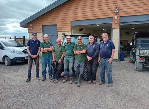 Happy group of volunteers in front of workshop